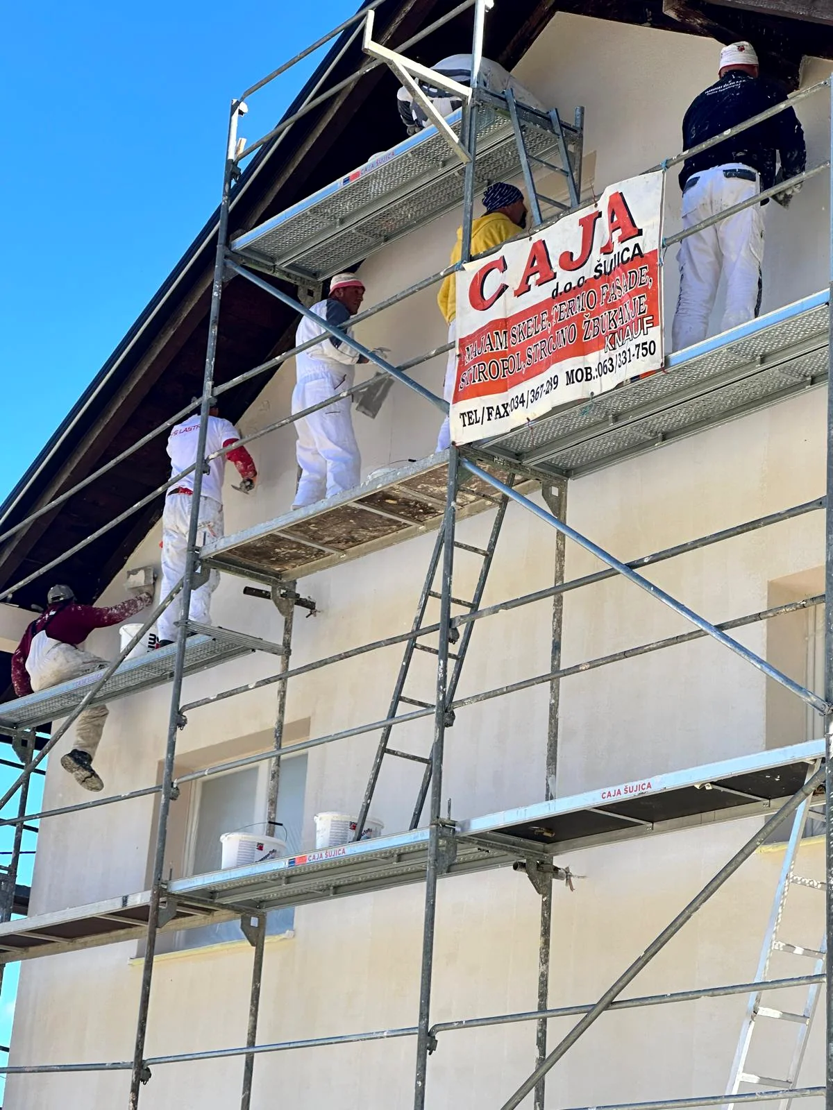 Radnici CAJA d.o.o. Šujica na skeli, s natpisom tvrtke